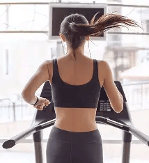 Fit girl en train de courir sur un tapis de course chez fit and coach 