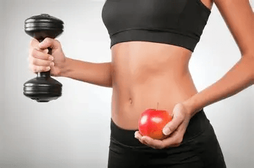 Fit girl avec un haltère et une pomme à Fit And Coach