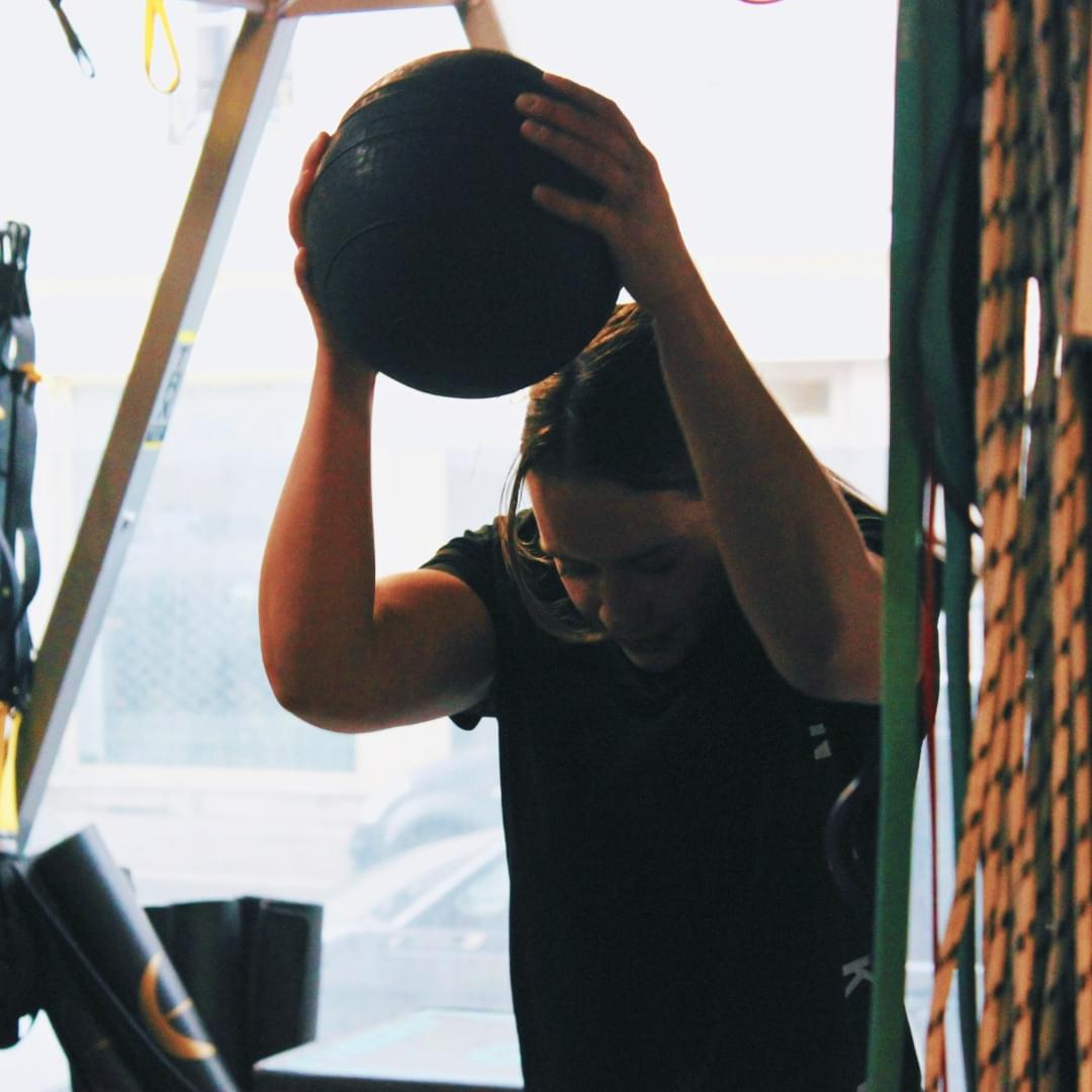 Fitgirl qui effectue un slam avec un slamball mouvement de jetté de balle lourde au sol